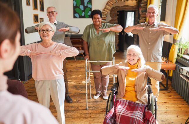 A group fitness class of older adults concentrating on mobility exercises.