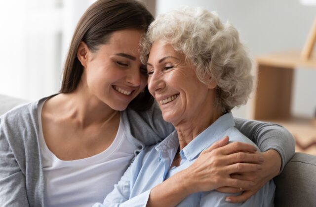 A younger daughter hugs her elderly mother.