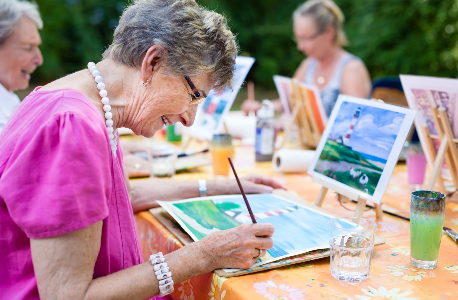 A group of older adults painting outside and enjoying social connections.