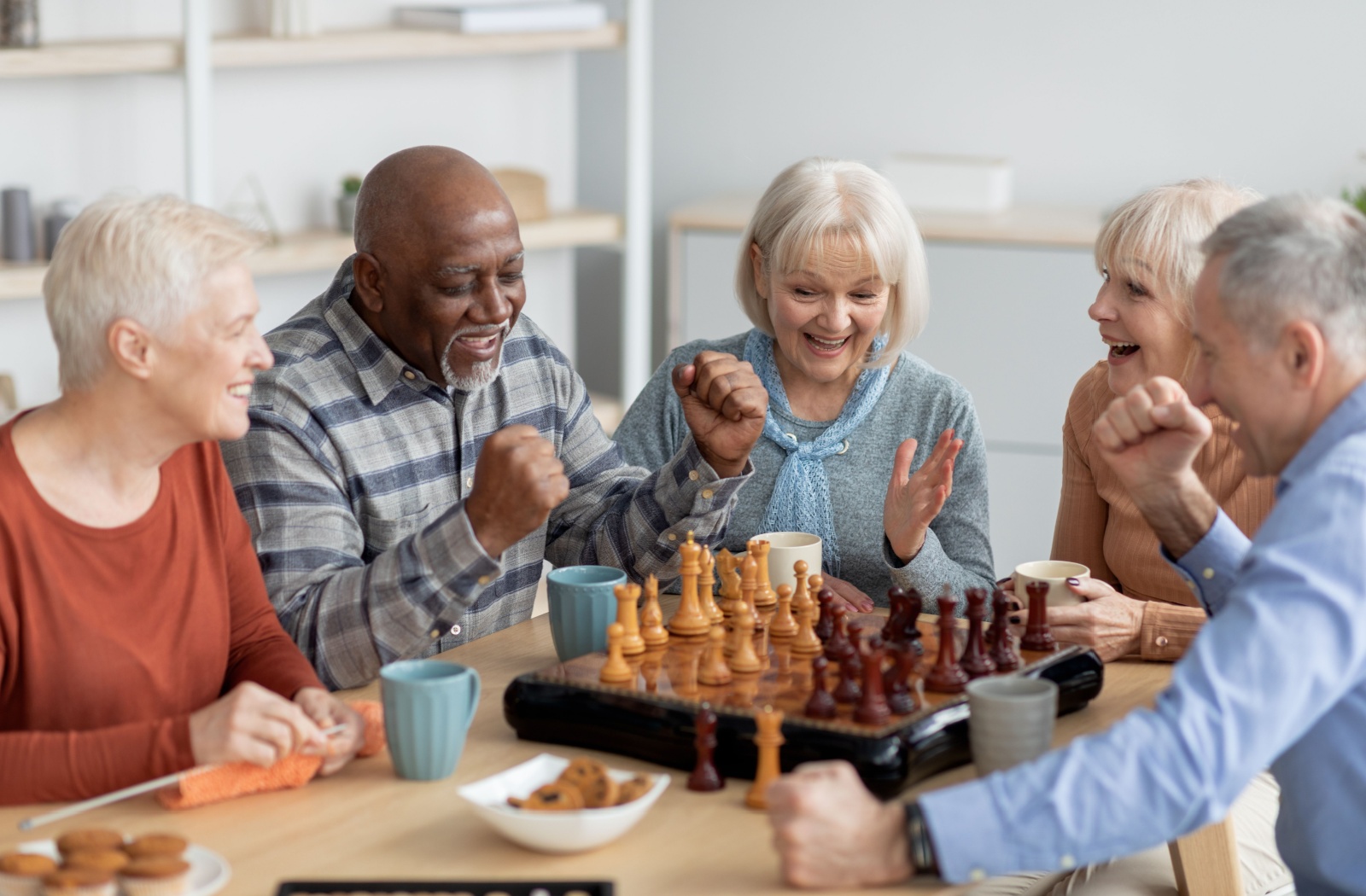 A group of memory care residents playing a board game that helps stimulate cognitive function.