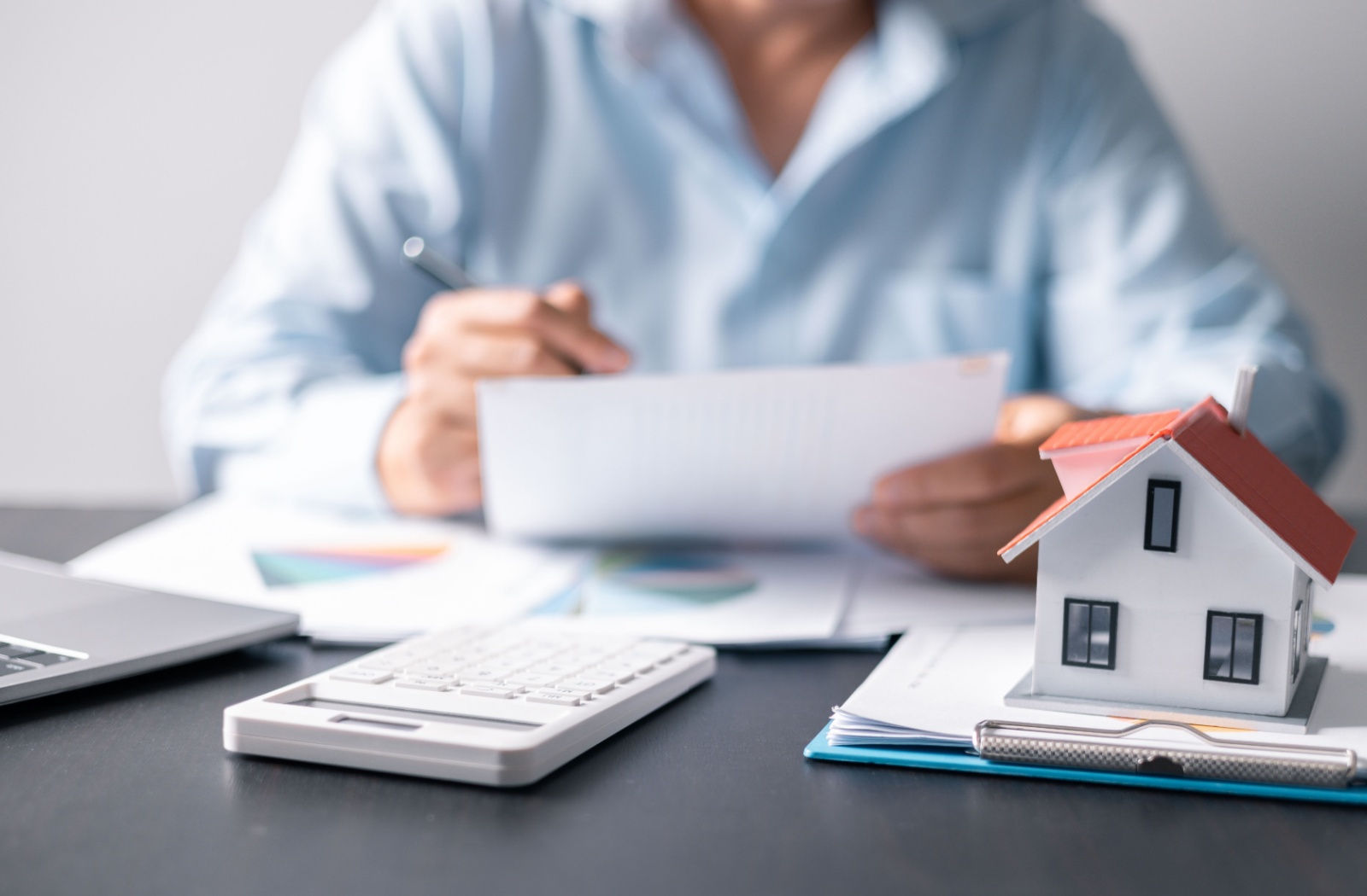 A man is choosing between a retirement home and assisted living. On his desk, he has a small house model and calculator.